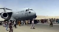 Hunderte Menschen laufen neben einer Boeing C-17 der United States Air Force, die auf dem Rollfeld des Kabul International Airport fährt.