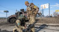 Ukrainische Soldaten hantieren mit Ausrüstung aus einem beschädigten Militärfahrzeug nach Kämpfen in Charkiw.