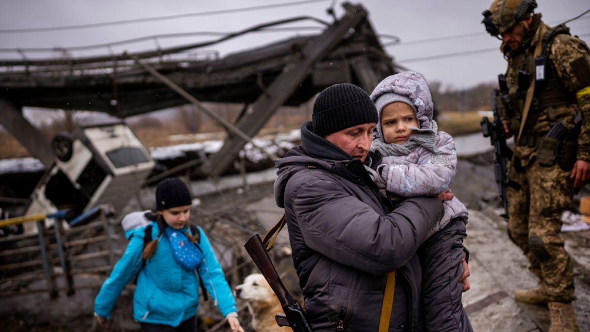 Familien fliehen, nachdem russische Truppen eine Brücke am Stadtrand von Kiew zerstört haben. (Foto)