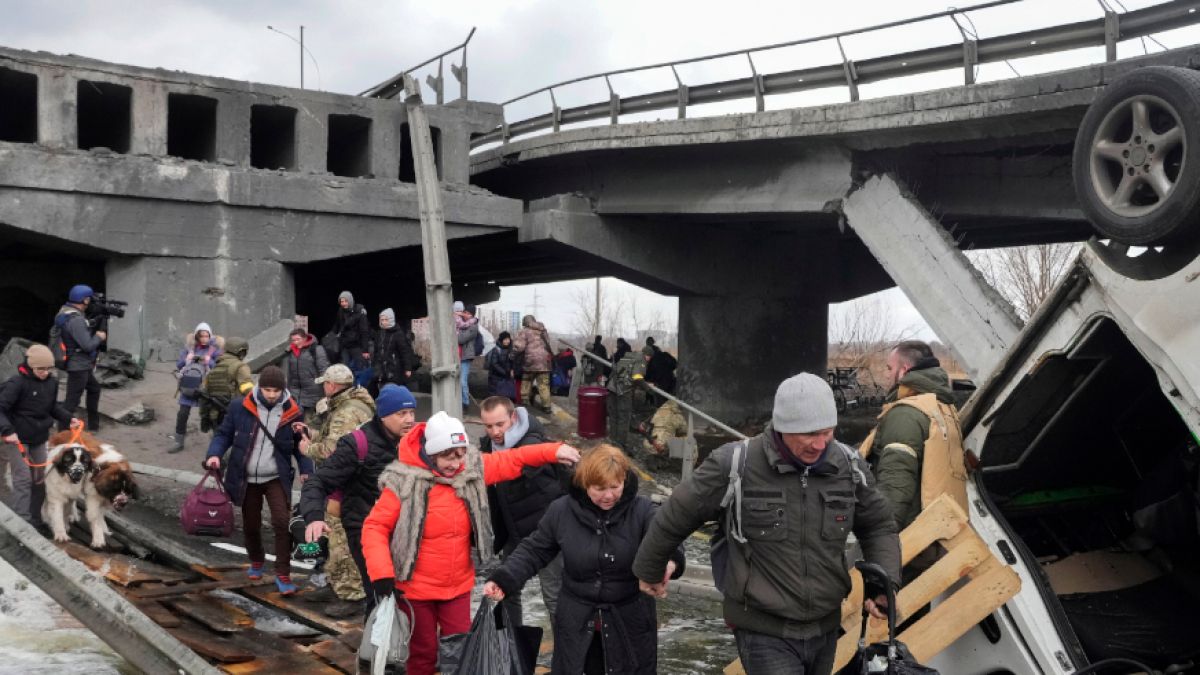 Menschen überqueren einen improvisierten Weg unter einer zerstörten Brücke auf der Flucht aus der Stadt Irpin in der Nähe von Kiew. (Foto)