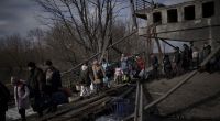 Ukrainer überqueren einen improvisierten Weg unter einer zerstörten Brücke auf der Flucht vor russischen Angriffen aus Irpin, am Stadtrand von Kiew, Ukraine.