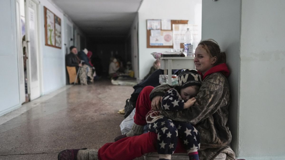 Eine Frau sitzt weinend auf dem Boden im Flur eines Krankenhauses in Mariupol, und umarmt eines ihrer Kinder. Zwei ihrer drei Kinder wurden während des Beschusses der Stadt getötet. (Foto)
