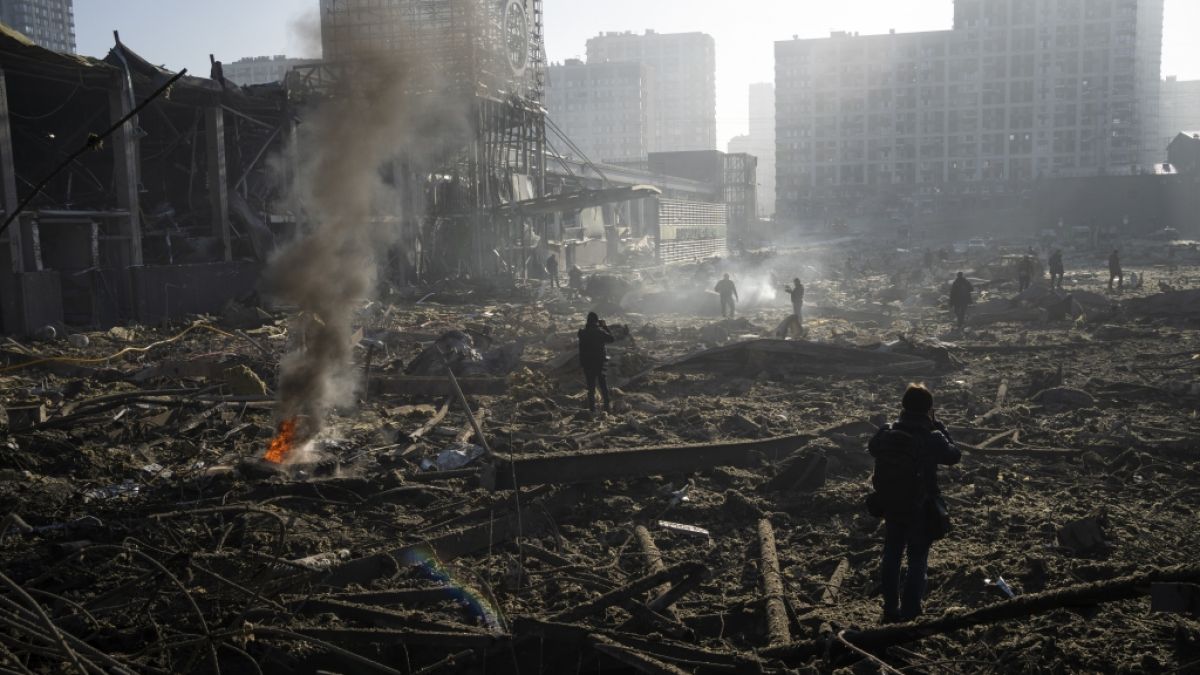 Menschen gehen durch die rauchenden Trümmer inmitten der Zerstörung, die nach dem Beschuss eines Einkaufszentrums in Kiew entstanden ist. (Foto)