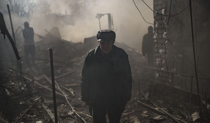 Ein Mann steht am 24.03.2022 inmitten des Rauchs eines brennenden Hauses, das nach einem russischen Angriff in Charkiw zerstört wurde. (Foto)