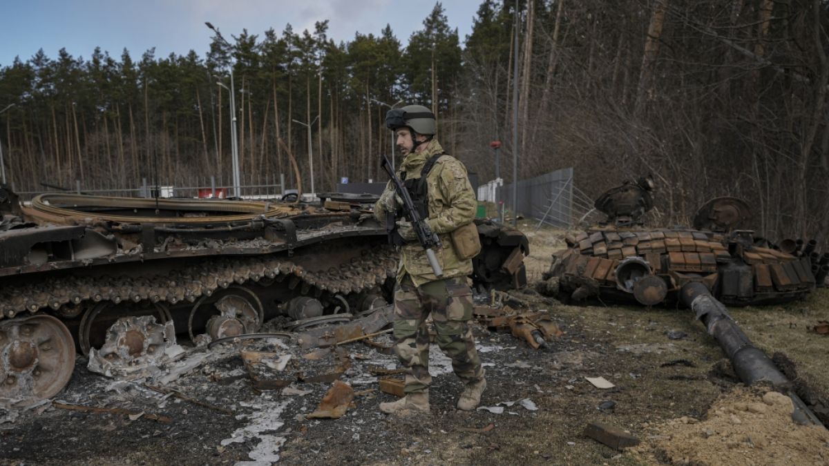 Ein ukrainischer Soldat läuft an zerstörten russischen Panzern vorbei. (Foto)
