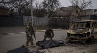 Zwei ukrainische Soldaten bergen die Überreste von vier getöteten Zivilisten aus einem verkohlten Fahrzeug in Butscha.
