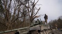 Ukrainische Soldaten posieren auf einem zerstörten Russen-Panzer.