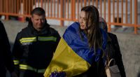 Eine Geflüchtete trägt eine ukrainische Fahne, nachdem sie mit einer Fähre die Grenze überquert hat.