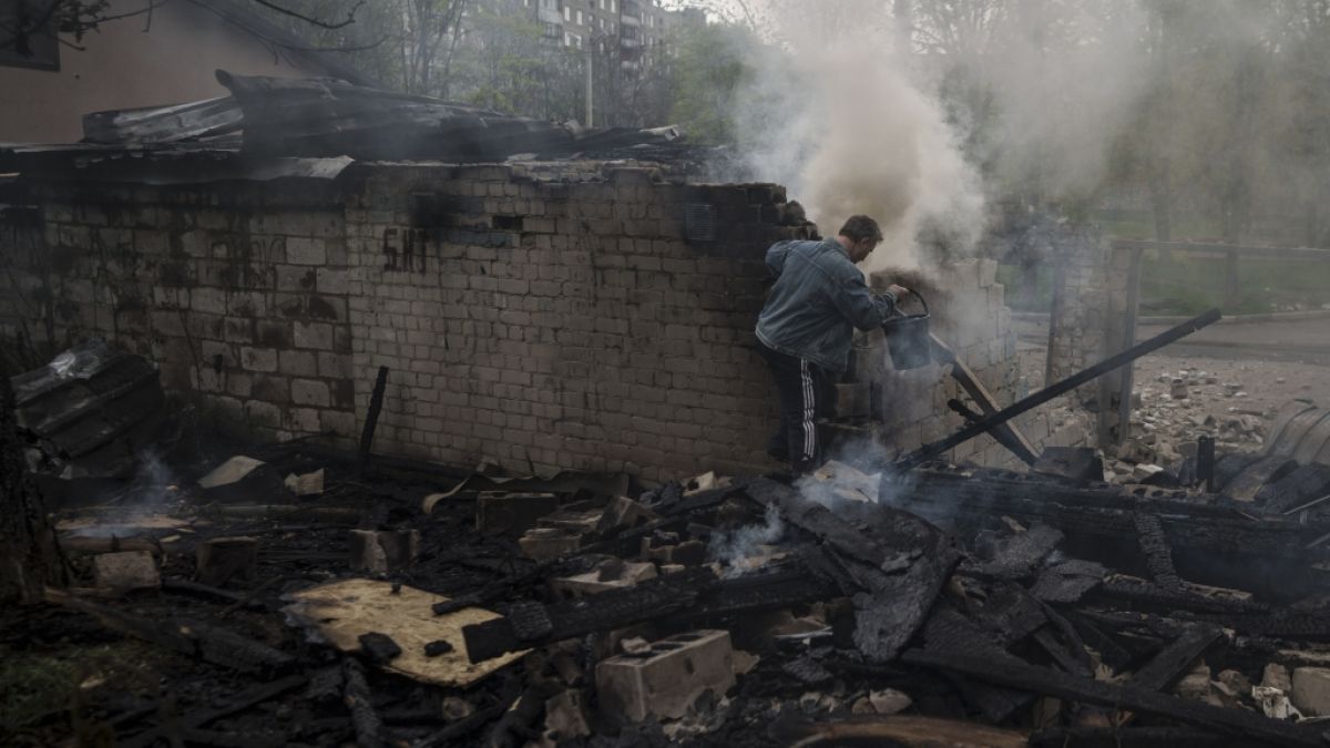 Ein Mann versucht, nach einem russischen Bombardement eines Wohnviertels, ein Feuer zu löschen. (Foto)