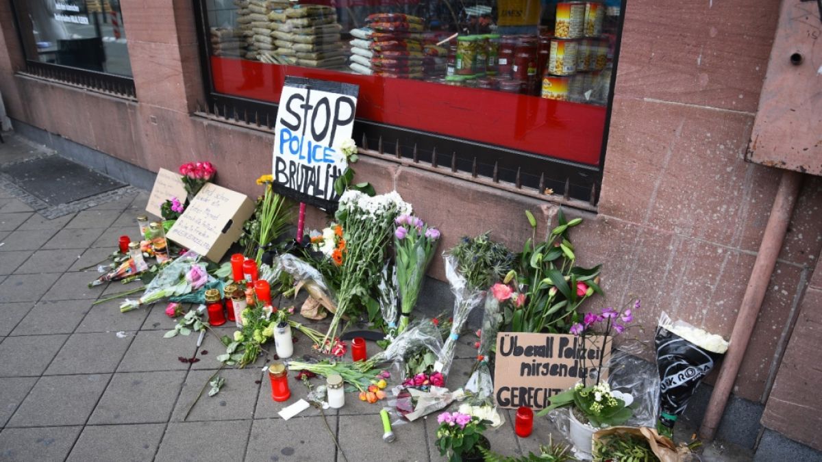 Blumen, Kerzen und Schilder liegen und stehen an dem Ort, an dem am Montag (02.05.2022) ein Mann nach einer Polizeikontrolle gestorben ist. (Foto)