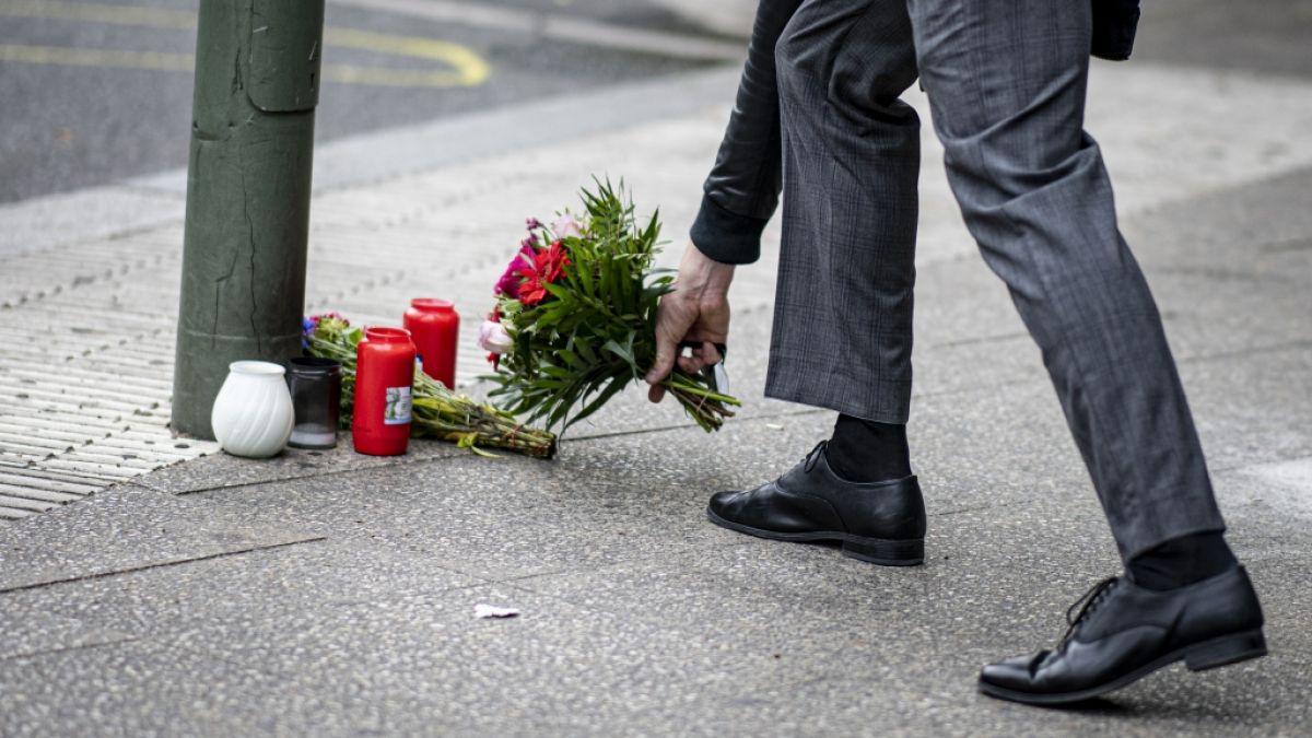 Ein Mann legt Blumen auf den Bürgersteig an der Tauentzienstraße auf den Boden. (Foto)