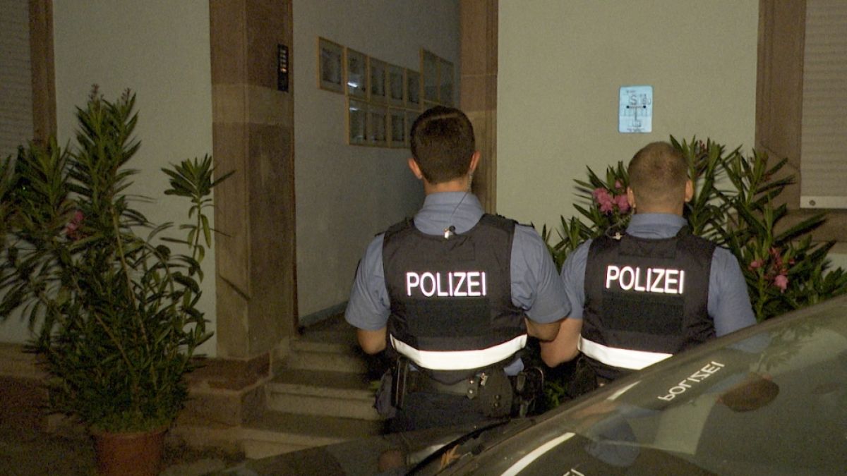 Polizeibeamte stehen vor einem Hauseingang. In Saarbrücken ist eine Mutter mit ihren zwei kleinen Kindern von einer Brüstung gefallen. (Foto)