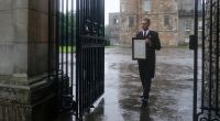 Ein Angestellter hängt an den Toren des Palace of Holyroodhouse in Edinburgh eine Nachricht über den Tod von Königin Elizabeth II. aus.