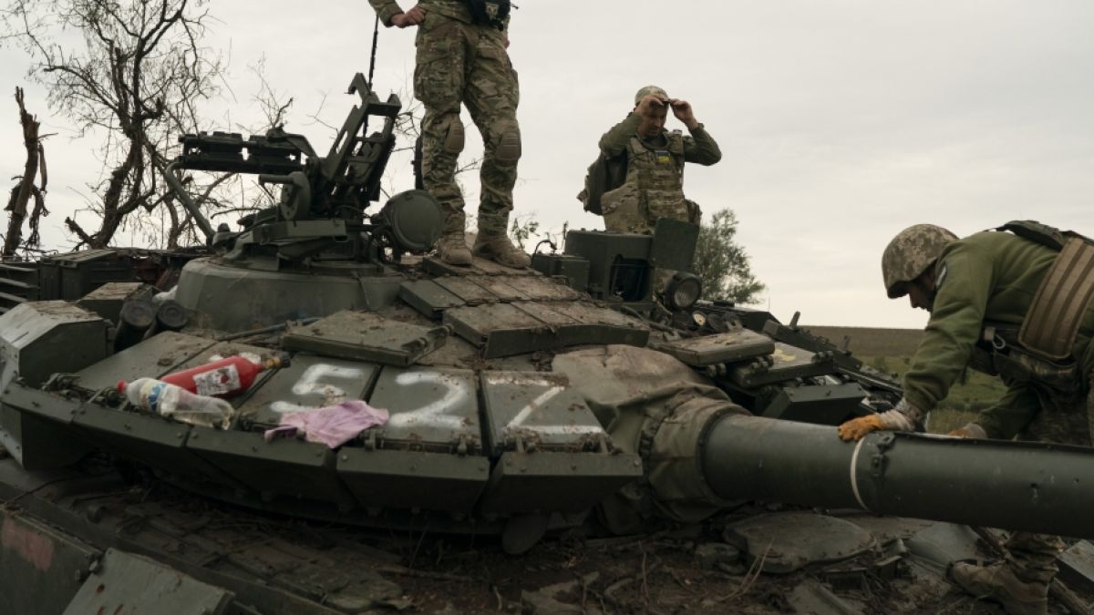 Ukrainische Soldaten stehen auf einem zerstörten russischen Panzer in der Region Charkiw. (Foto)