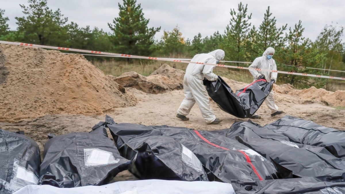 Ermittler tragen den Leichensack mit den sterblichen Überresten eines ukrainischen Soldaten bei einer Begräbnisstätte in Lyman. Dort hatten Kreml-Kämpfer offenbar auch wahllos Zivilisten getötet. (Foto)