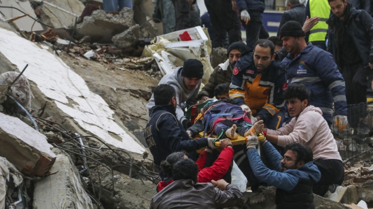 Menschen und Rettungskräfte bergen eine Person auf einer Bahre aus einem eingestürzten Gebäude. Tausende Menschen werden unter den Trümmern vermisst. (Foto)