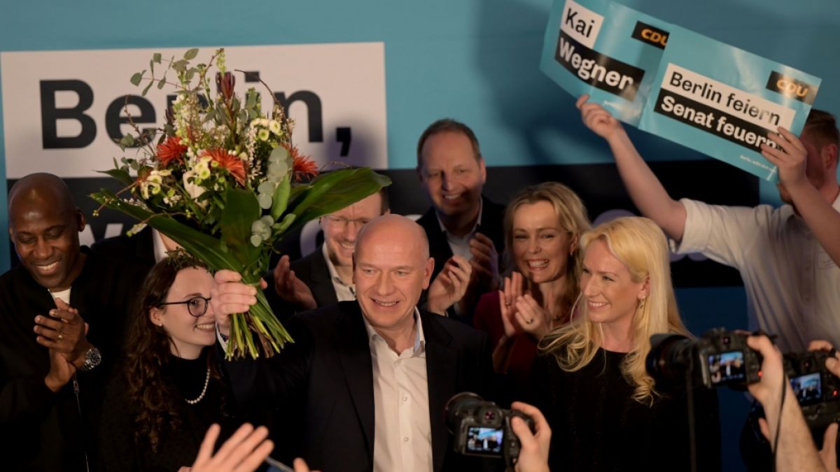 CDU-Spitzenkandidat Kai Wegner steht mit einem Blumenstrauß in der Hand neben seiner Partnerin Kathleen Kantar. (Foto)