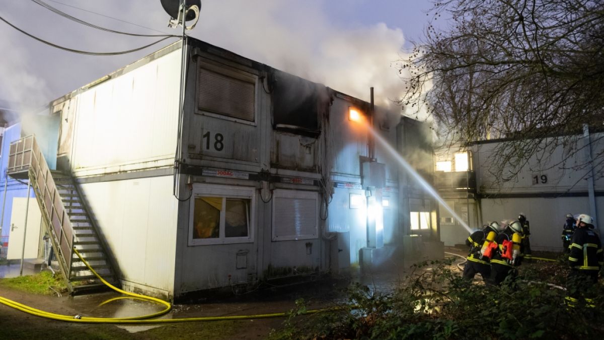 Feuerwehrleute löschen den verqualmten und teils brennenden Container einer Flüchtlingsunterkunft in Hamburg-Winterhude. (Foto)