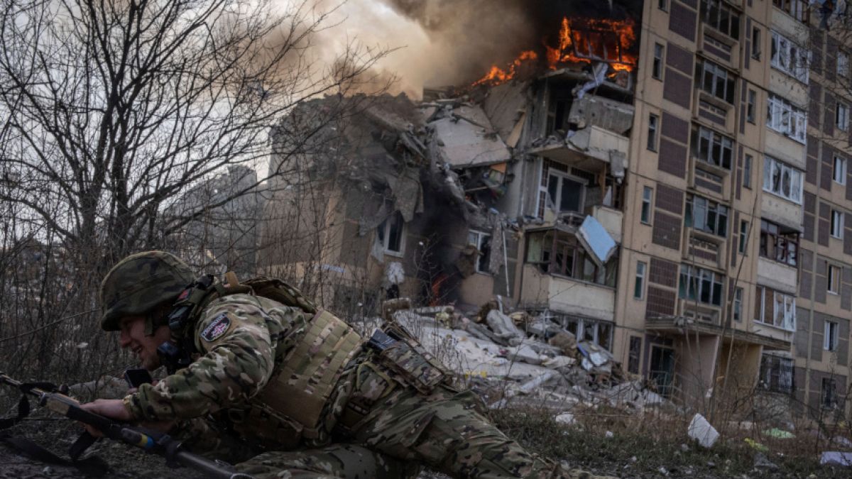 Ein ukrainischer Polizist geht vor einem brennenden Gebäude in Awdijiwka in Deckung, das bei einem Luftangriff getroffen wurde. (Foto)