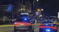 Menschen und Polizeiautos stehen am Tatort. Bei Schüssen während einer Geburtstagsparty im US-Bundesstaat Alabama sind mehrere Menschen getötet worden.