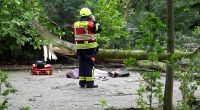 Ein Feuerwehrmann steht vor der abgedeckten Leiche einer Frau, die während des Sturms Poly von einem umgestürzten Baum tödlich verletzt wurde. Nach Polizeiangaben erlag die Frau noch vor Ort ihren Verletzungen.