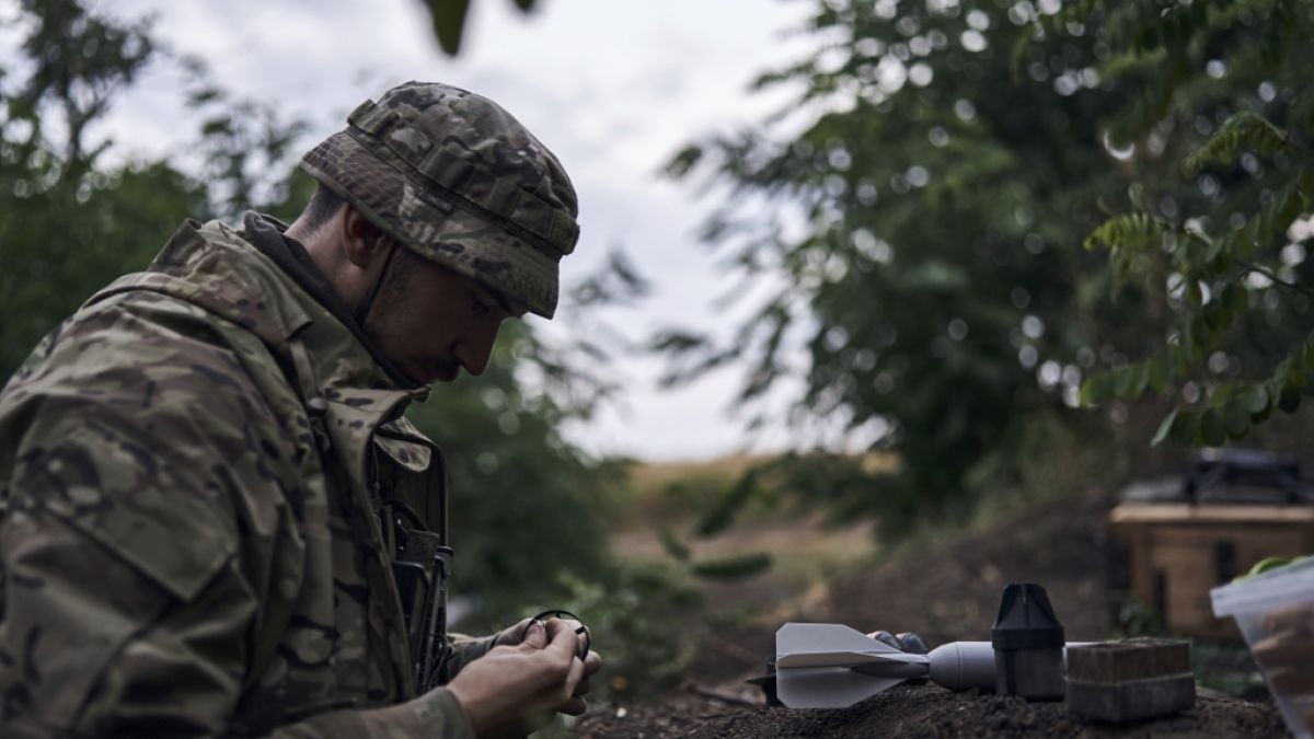 Ein ukrainischer Soldat lädt eine Bombe auf eine Drohne. (Foto)