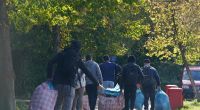 Flüchtlinge aus Syrien und der Türkei gehen mit ihrem Gepäck zur Erstaufnahmeeinrichtung.