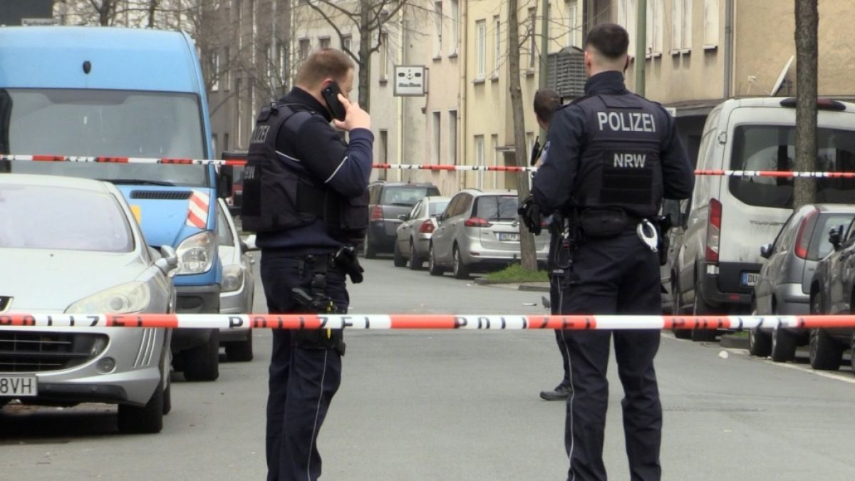 Zwei Beamte stehen an dem abgesperrten Tatort in Duisburg. (Foto)