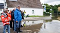 Markus Söder verschafft sich einen Überblick zur Hochwasserlage an einer überfluteten Straße nahe der Donaubrücke in Günzburg.