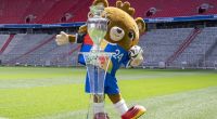 Albärt, Maskottchen der Fußball-EM 2024, präsentiert den Fußball-EM-Pokal in der Allianz Arena.