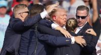 Donald Trump wird von Agenten des Secret Service umringt, als ihm bei einer Wahlkampfveranstaltung von der Bühne geholfen wird.