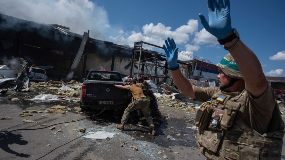 Rettungskräfte und Soldaten schieben ein beschädigtes Auto, nachdem eine russische Rakete einen Supermarkt in Kostjantyniwka in der ukrainischen Region Donezk getroffen hat. (Foto)