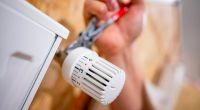 Heizungsausfall im Winter vorbeugen: Ein Handwerker arbeitet an einem Heizkörper