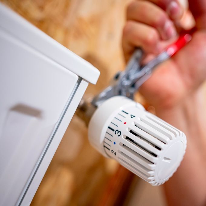 Heizungsausfall im Winter vorbeugen: Ein Handwerker arbeitet an einem Heizkörper