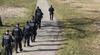 Mehrere Einsatzkräfte der Polizei suchen ein Gebiet rund um den Fundort der Babyleiche ab.