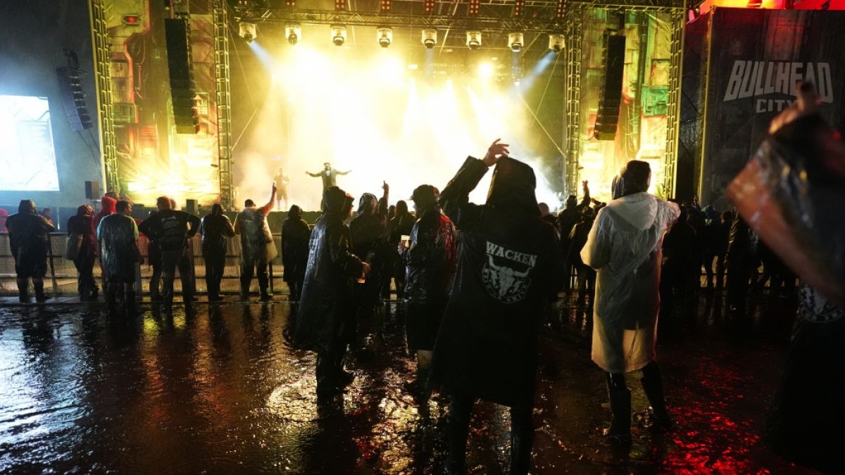 Metal-Fans feiern spät in der Nacht auf dem Festivalgelände des Wacken Open Air (WOA) vor einer Bühne. (Foto)