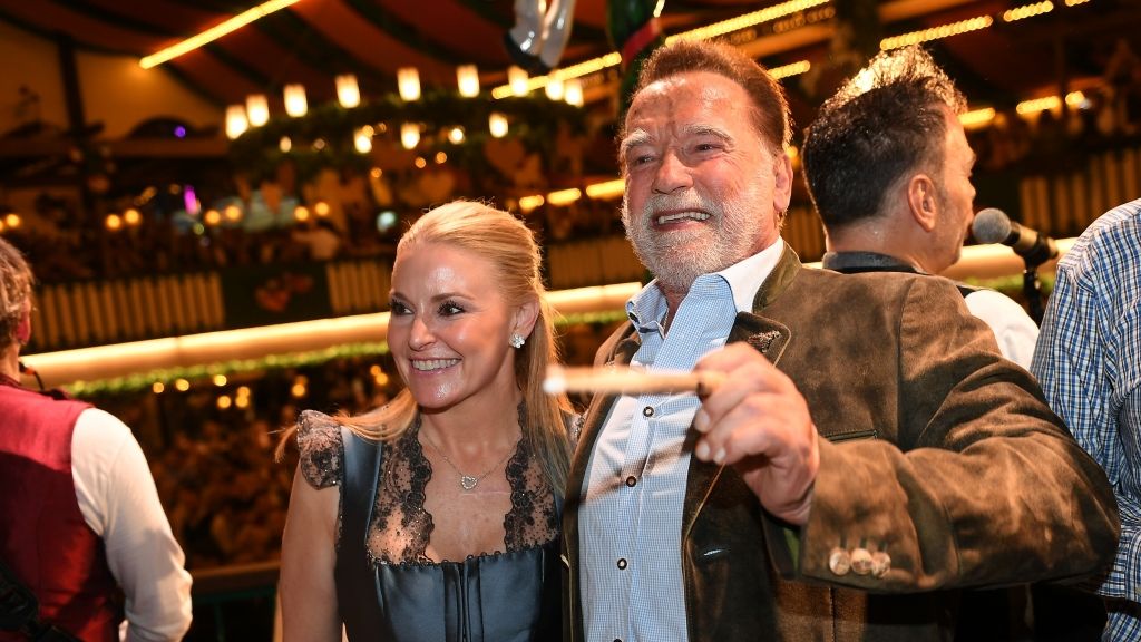 Schauspieler Arnold Schwarzenegger (r) und und seine Lebensgefährtin Heather Milligan stehen im Marstall-Festzelt auf der Bühne und dirigieren. (Foto)