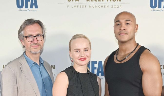 Luise von Finckh steht gemeinsam mit Produzent Jörg Winger und Schauspieler Malick Bauer auf dem roten Teppich.