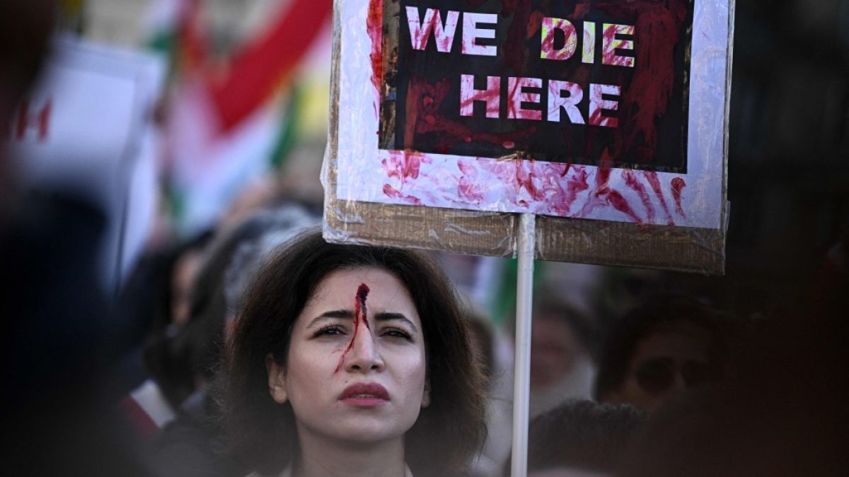 Eine Teilnehmerin mit einem roten blut&auml;hnlichen Fleck auf der Stirn h&auml;lt ein Plakat bei einer Kundgebung zur Unterst&uuml;tzung der Demonstranten im Iran. (Foto)