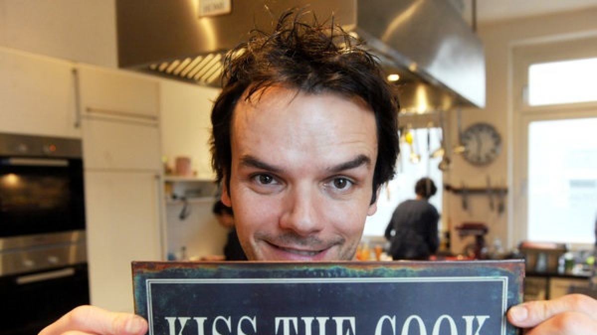 Fernseh-Koch Steffen Henssler bei der Pr&auml;sentation seines Kochbuchs "Hauptsache lecker!" mit einem Schild mit der Aufschrift "Kiss The Cook". (Foto)