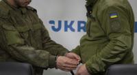 Ein ukrainischer Sicherheitsbeamter (r.) eskortiert einen in Handschellen geführten Chinesen (l.), der in Donezk gefangen genommen wurde, zu einer Pressekonferenz in Kiew.