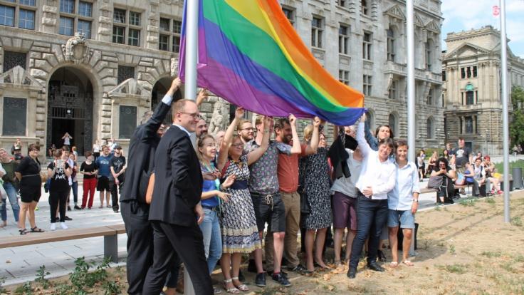 Leipzigs Bürgermeister Ulrich Hörning (vorn) hisst mit CSD-Verantwortlichen die Regenbogenflagge.