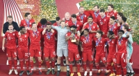 Die Spieler des FC Bayern München feiern mit der Trophäe.