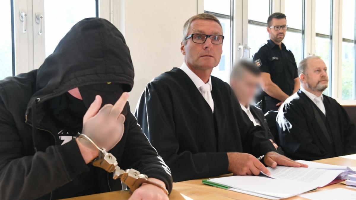 Der 19-j&auml;hriger Angeklagte (l) zeigt im Gerichtssaal im Landgericht den Mittelfinger. (Foto)