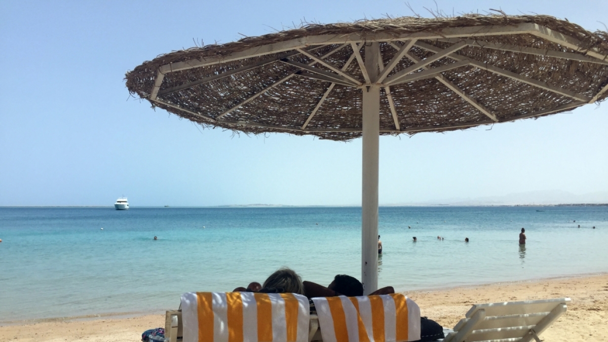 Eine Frau und ein Mann entspannen in Liegest&uuml;hlen unter einem Sonnenschirm an einem &ouml;ffentlichen Strand im &auml;gyptischen Hurghada. Vor wenigen Tagen wurden in dem beliebten Urlaubsort zwei tote Hotelg&auml;ste aufgefunden. (Foto)