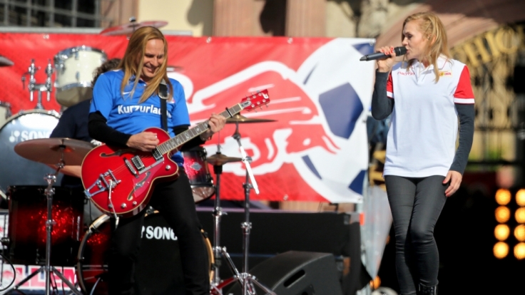 Silly (hier Sängerin Anna Loos im Union-Berlin-Shirt und Gitarrist Uwe Hassbecker im Hansa-Rostock-Trikot) traten bei der Aufstiegsfeier von RB Leipzig in Fan-Outfits anderer Vereine auf.