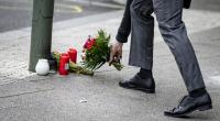 Ein Mann legt Blumen auf den Bürgersteig an der Tauentzienstraße auf den Boden.