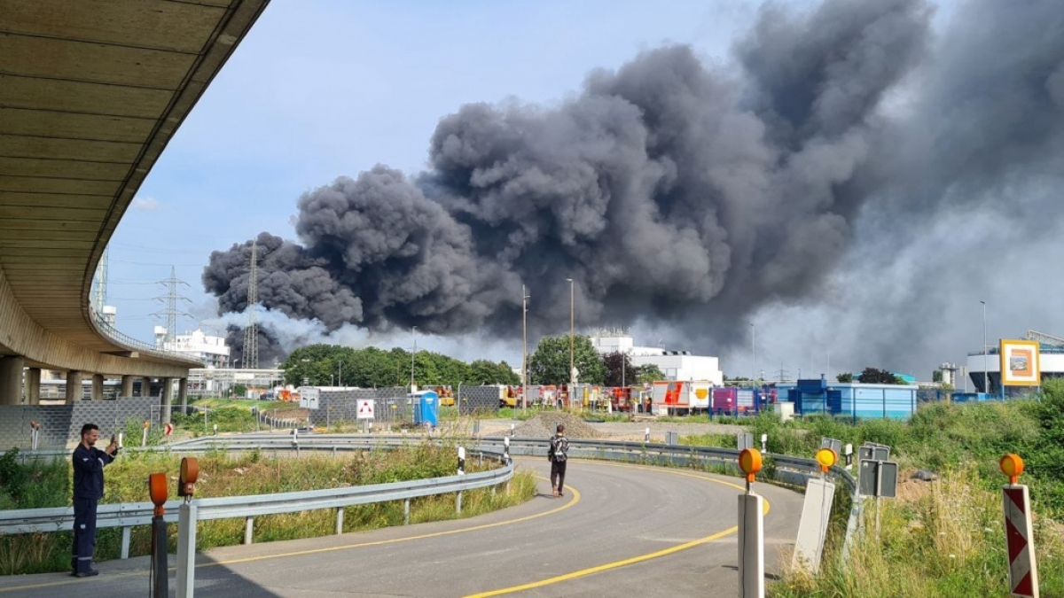 Eine dunkle Rauchwolke steigt &uuml;ber dem Chemiepark Leverkusen auf. Einsatzkr&auml;fte der Werkfeuerwehr sind im Einsatz. (Foto)