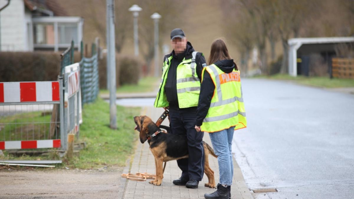 Polizisten suchen mit Polizeihund in der N&auml;he des Tatortes nach Spuren. (Foto)