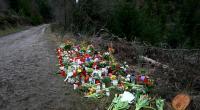 Ein Holzkreuz, zahlreiche Blumen, Kuscheltiere und Kerzen liegen am Tatort.